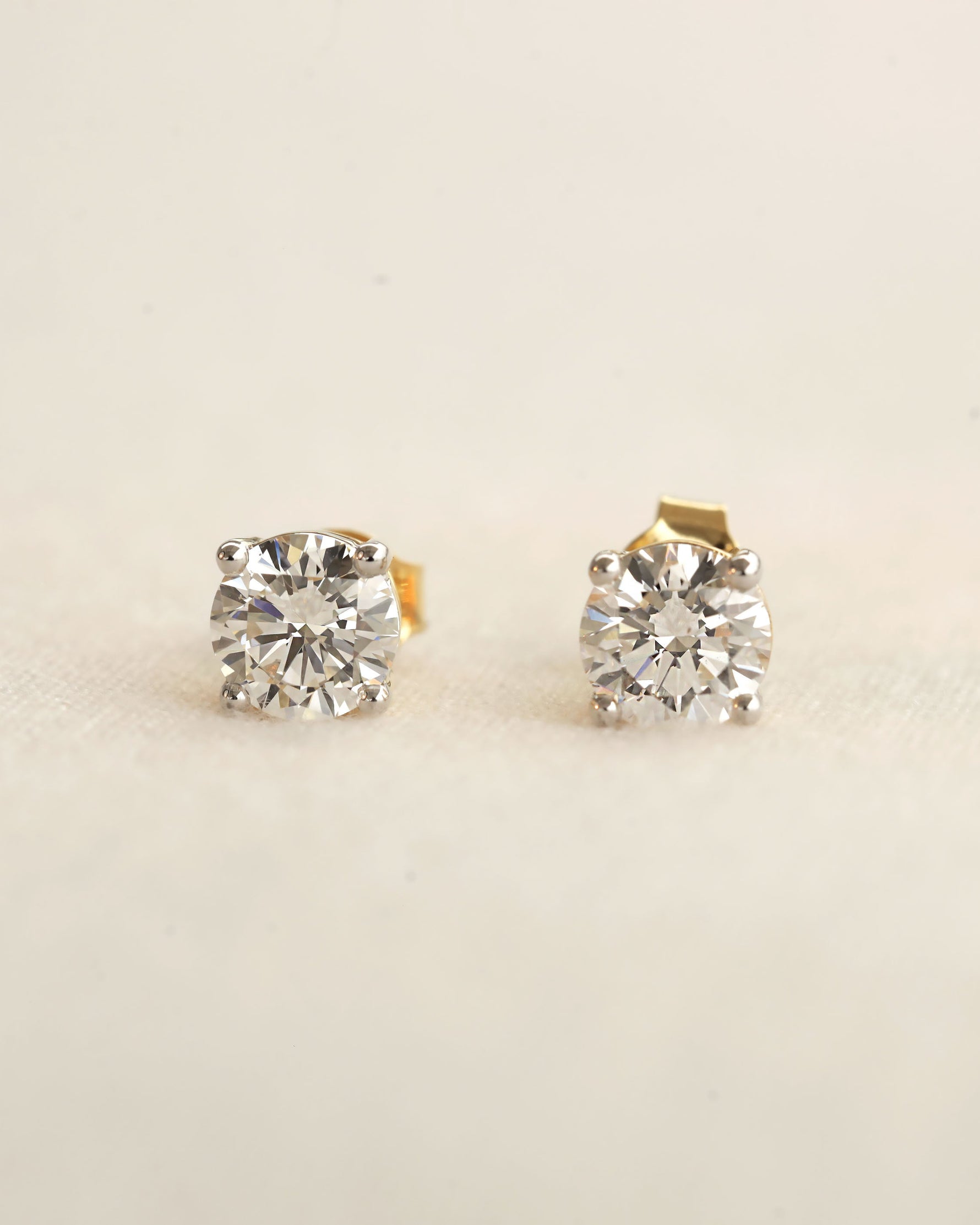 Pair of diamond stud earrings on a light beige background