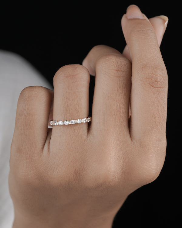 Hand wearing diamond eternity band in yellow gold.