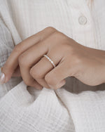 Hand wearing diamond eternity band in yellow gold.