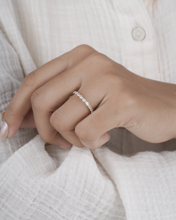 Hand wearing diamond eternity band in yellow gold.