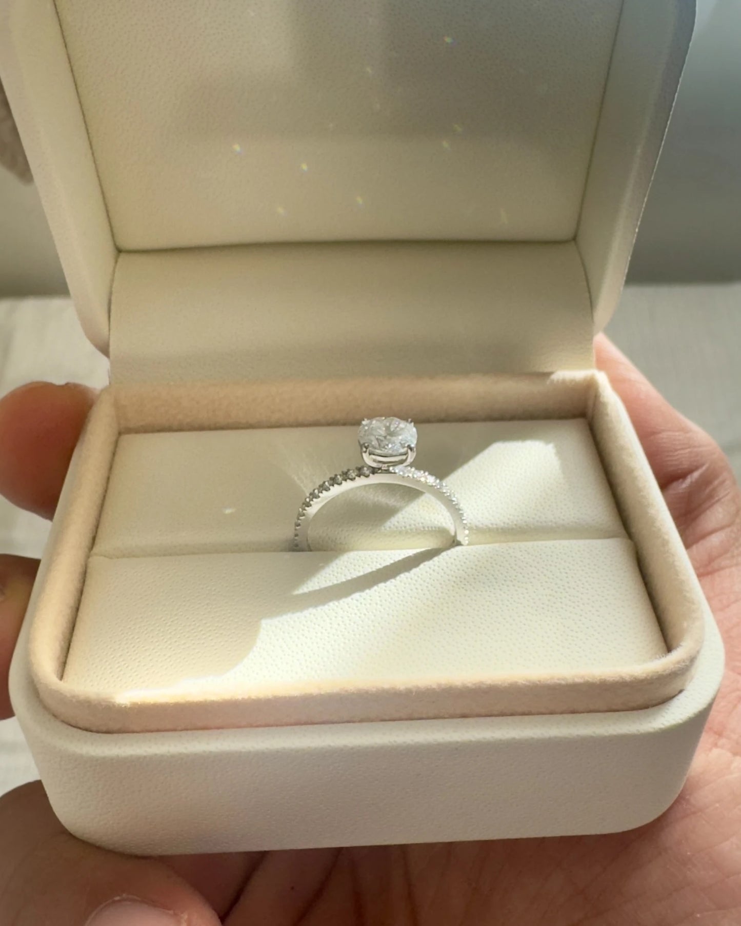 Close up of round diamond engagement ring with pave band.