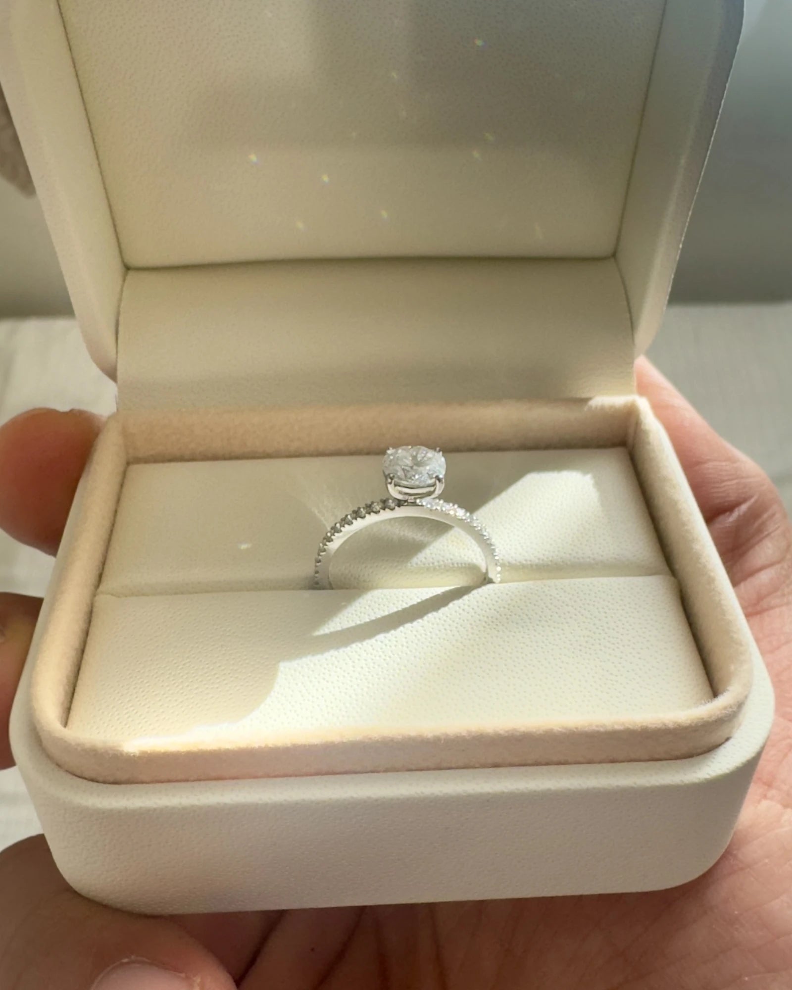 Close up of round diamond engagement ring with pave band.