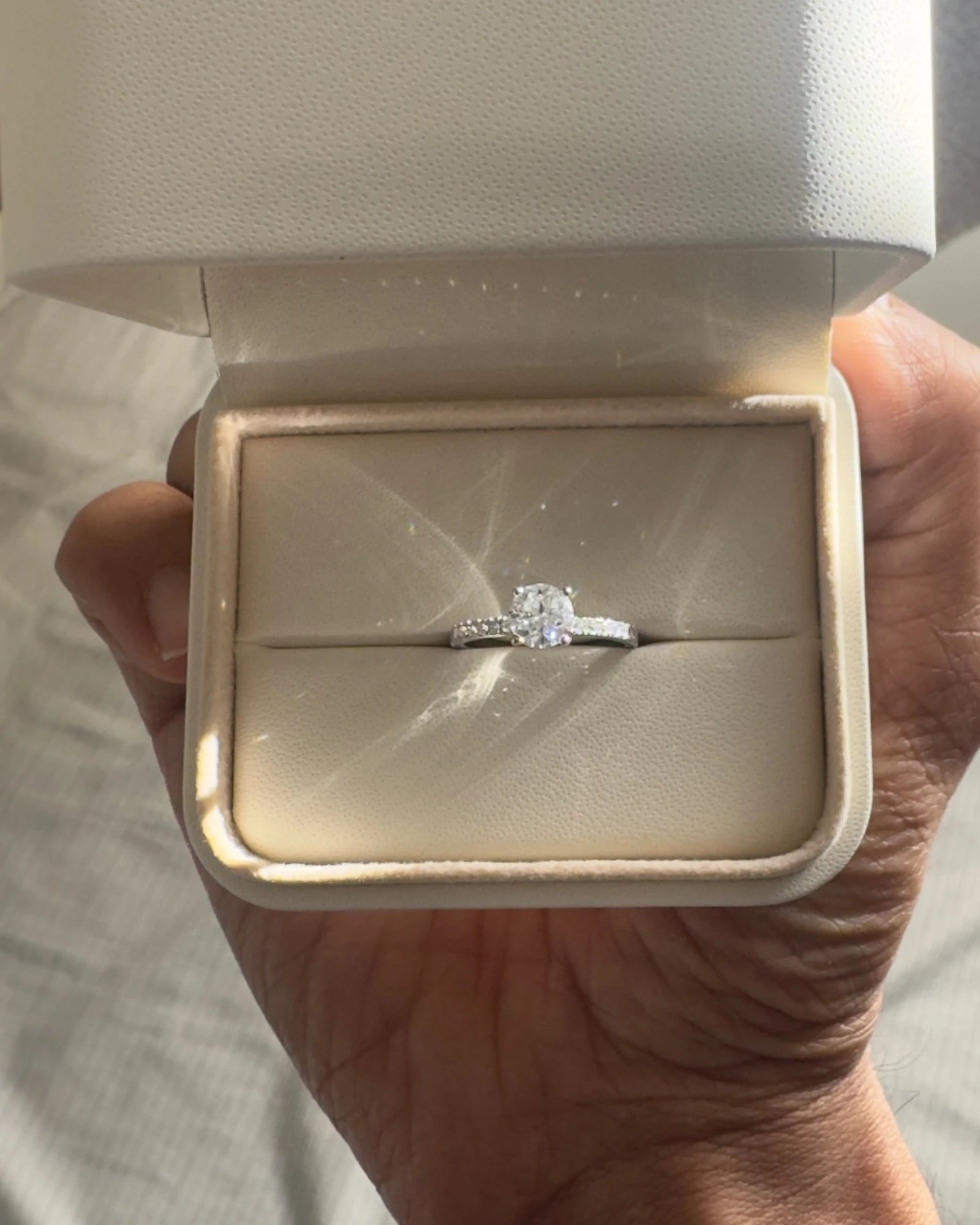 Close up of round diamond engagement ring with pave band.