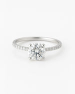 Close up of round diamond engagement ring with pave band.