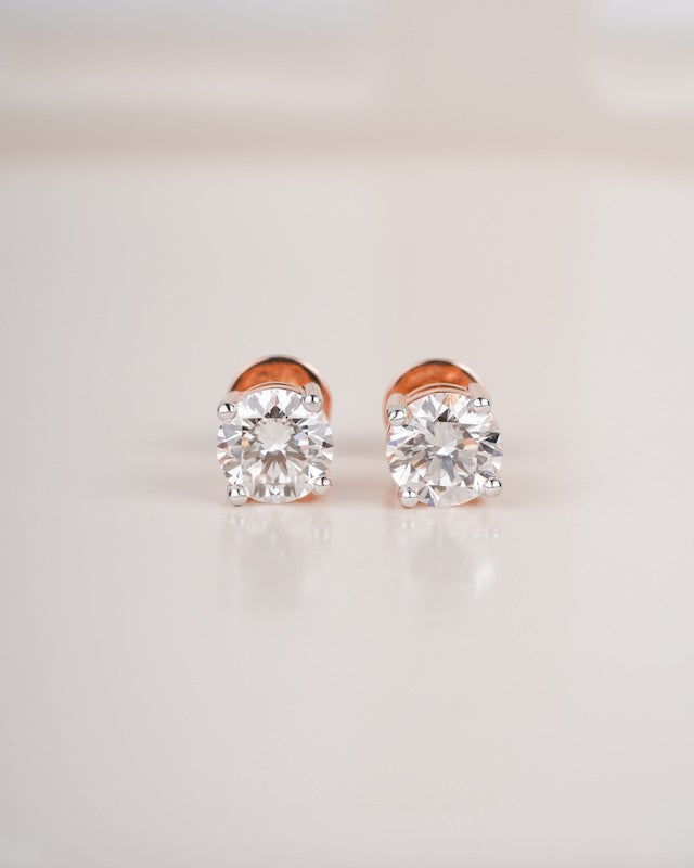 Rose gold diamond solitaire stud earrings on a white background.