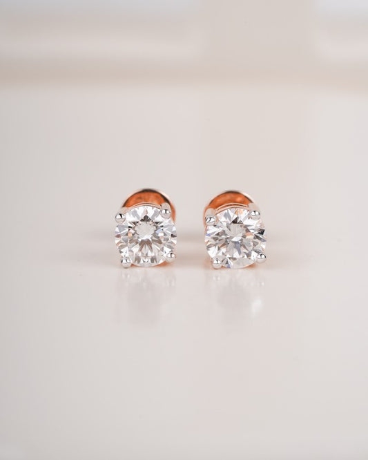 Rose gold diamond solitaire stud earrings on a white background.