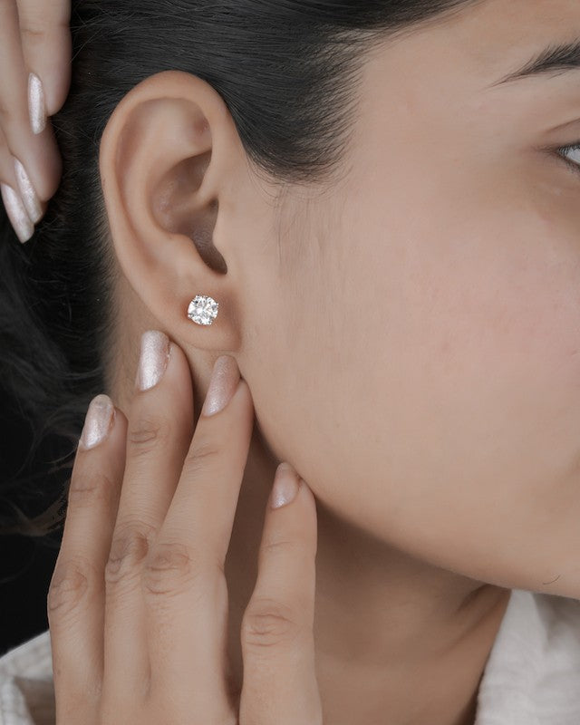 Person wearing rose gold diamond solitaire stud earrings.