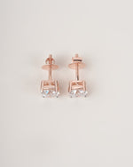 Rose gold diamond solitaire stud earrings on a white background.