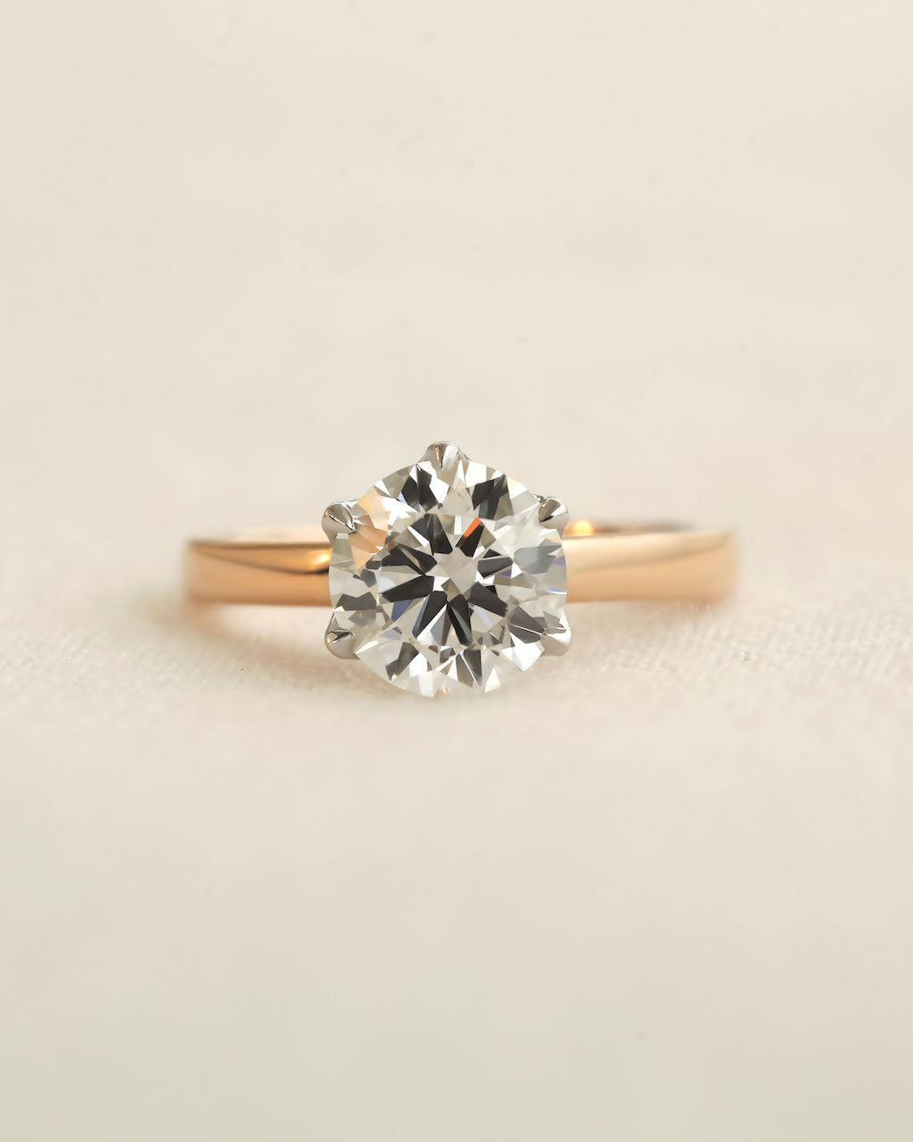 Close up shot of 2ct round brilliant engagement ring in rose gold with white gold prongs. 