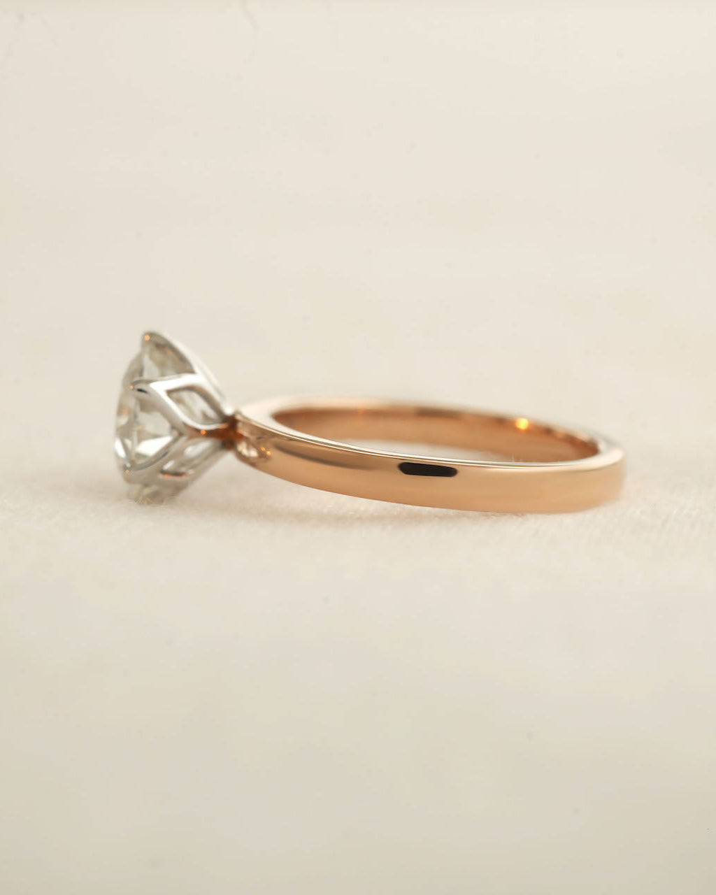 Side view of 2ct round brilliant engagement ring in rose gold with white gold prongs. 
