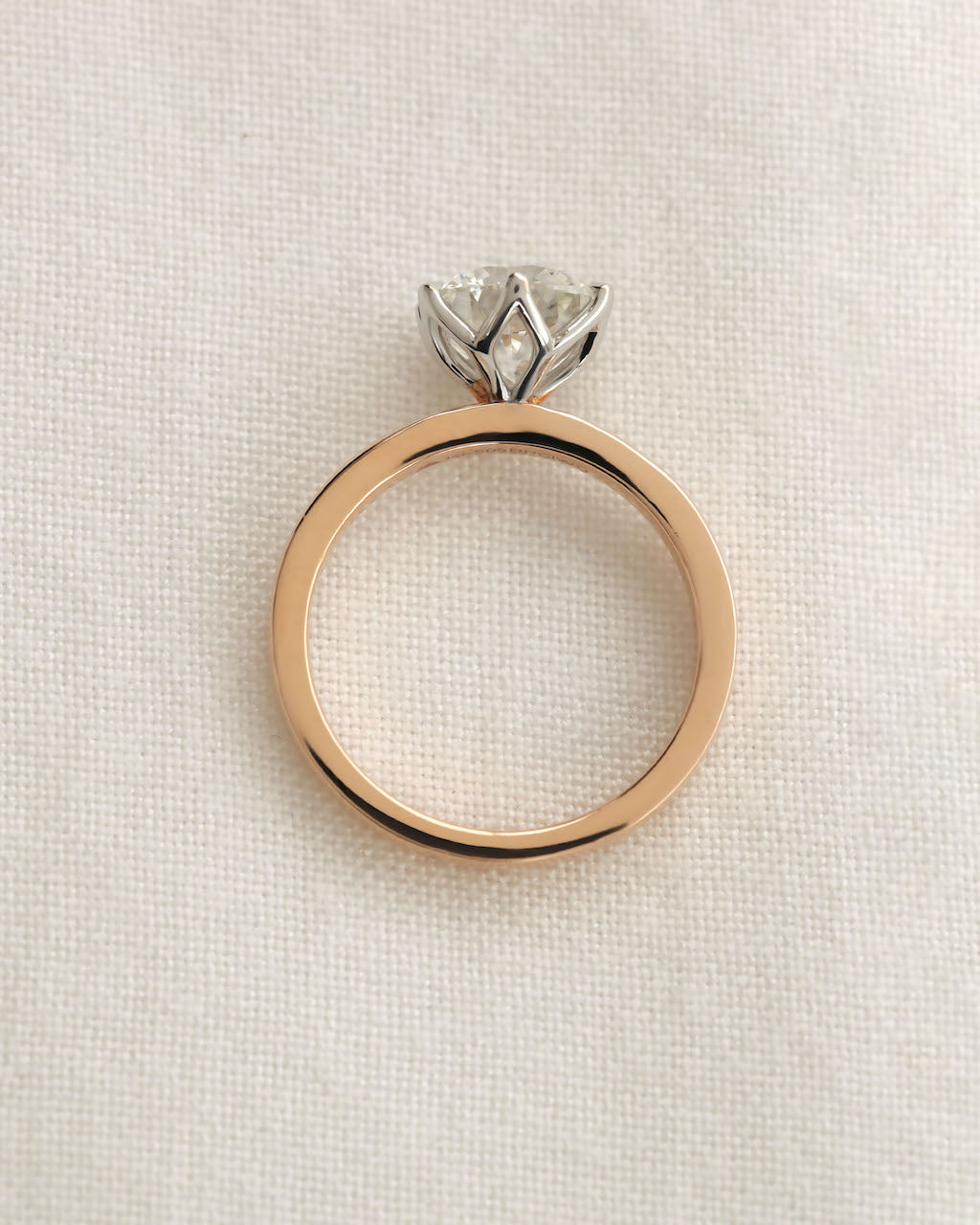 Close up shot of 2ct round brilliant engagement ring in rose gold with white gold prongs.

