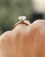 Hand wearing 2ct round brilliant engagement ring in rose gold with white gold prongs. 

