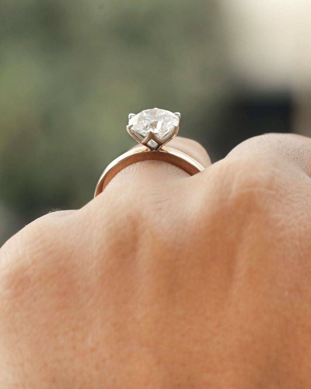 Hand wearing 2ct round brilliant engagement ring in rose gold with white gold prongs. 


