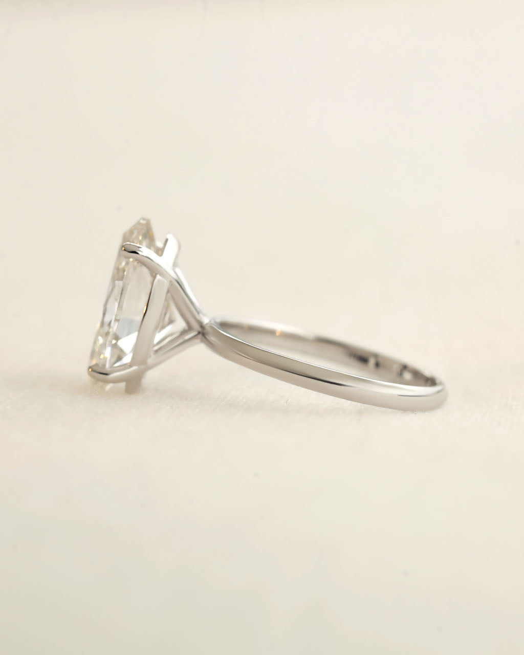 White Gold ring with a clear gemstone on a beige background