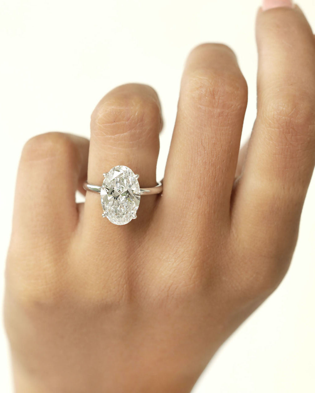 Hand wearing a diamond ring with a white background