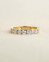 A yellow gold 7 stone half eternity diamond ring on a white background.
