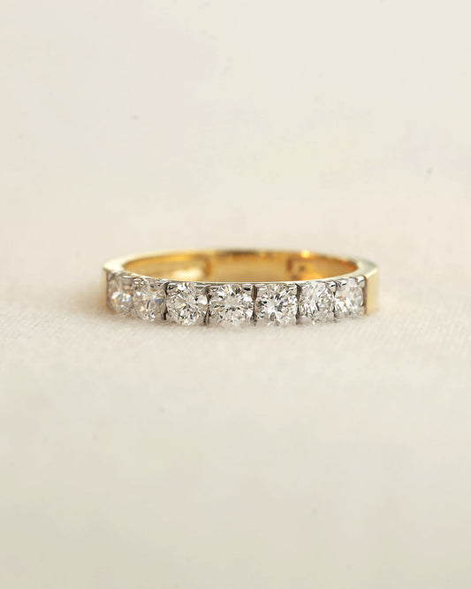 A yellow gold 7 stone half eternity diamond ring on a white background.