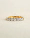 A yellow gold 7 stone half eternity diamond ring on a white background.