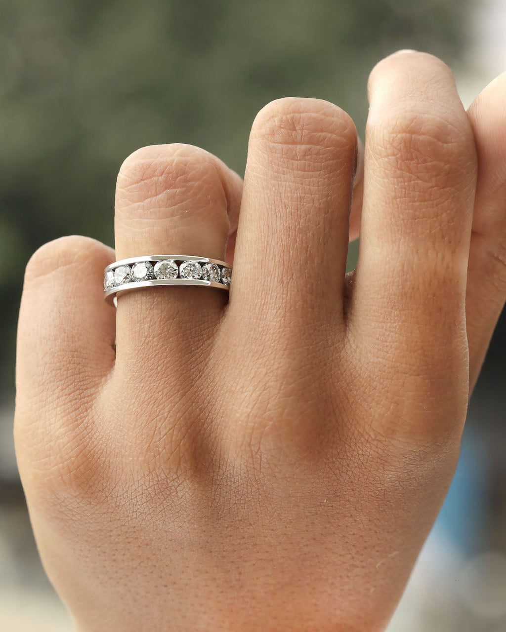 Hand wearing channel set diamond eternity ring in white gold.
