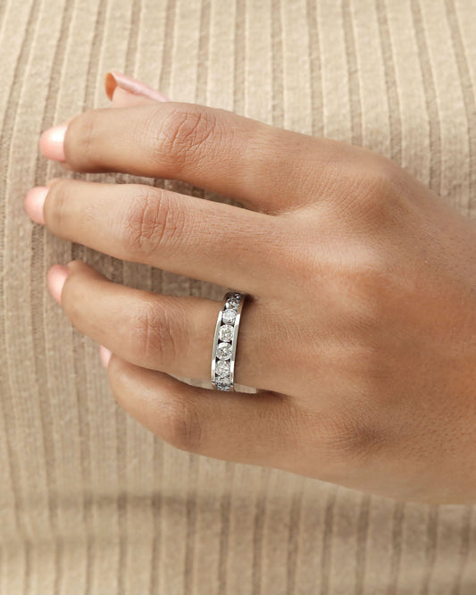 Hand wearing channel set diamond eternity ring in white gold.