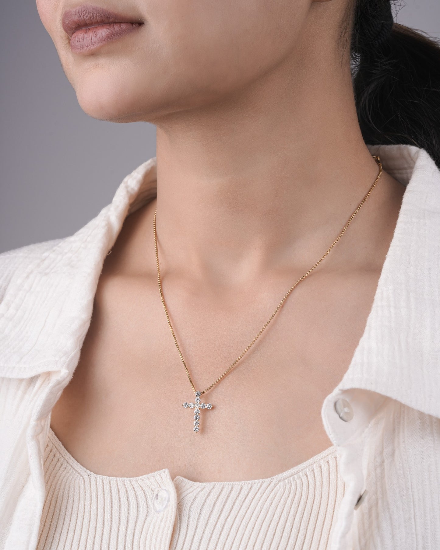Person wearing cross diamond pendant.