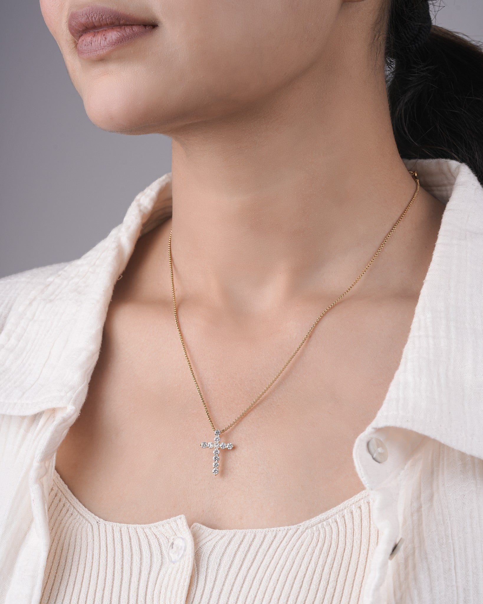 Person wearing cross diamond pendant.