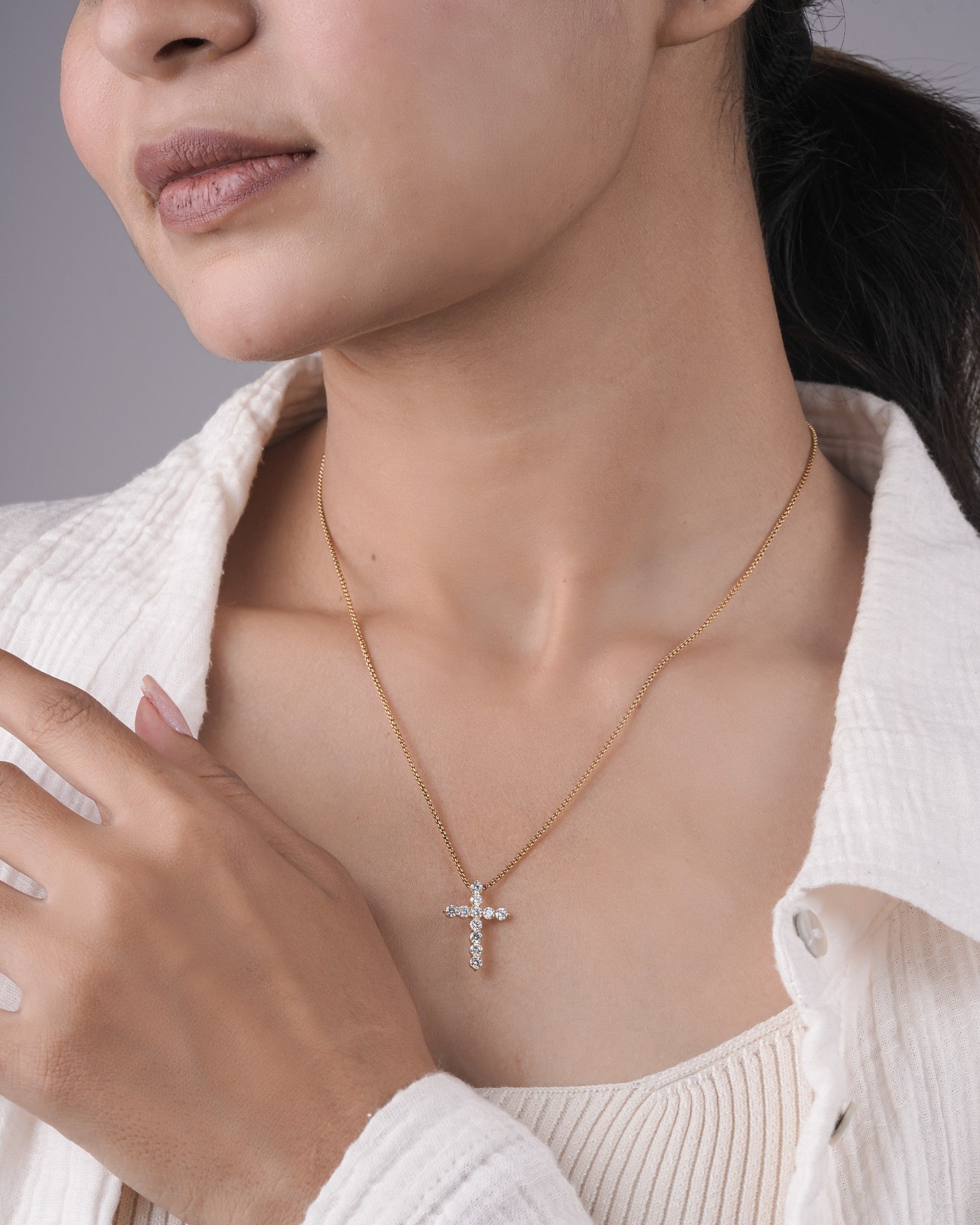 Person wearing cross diamond pendant.