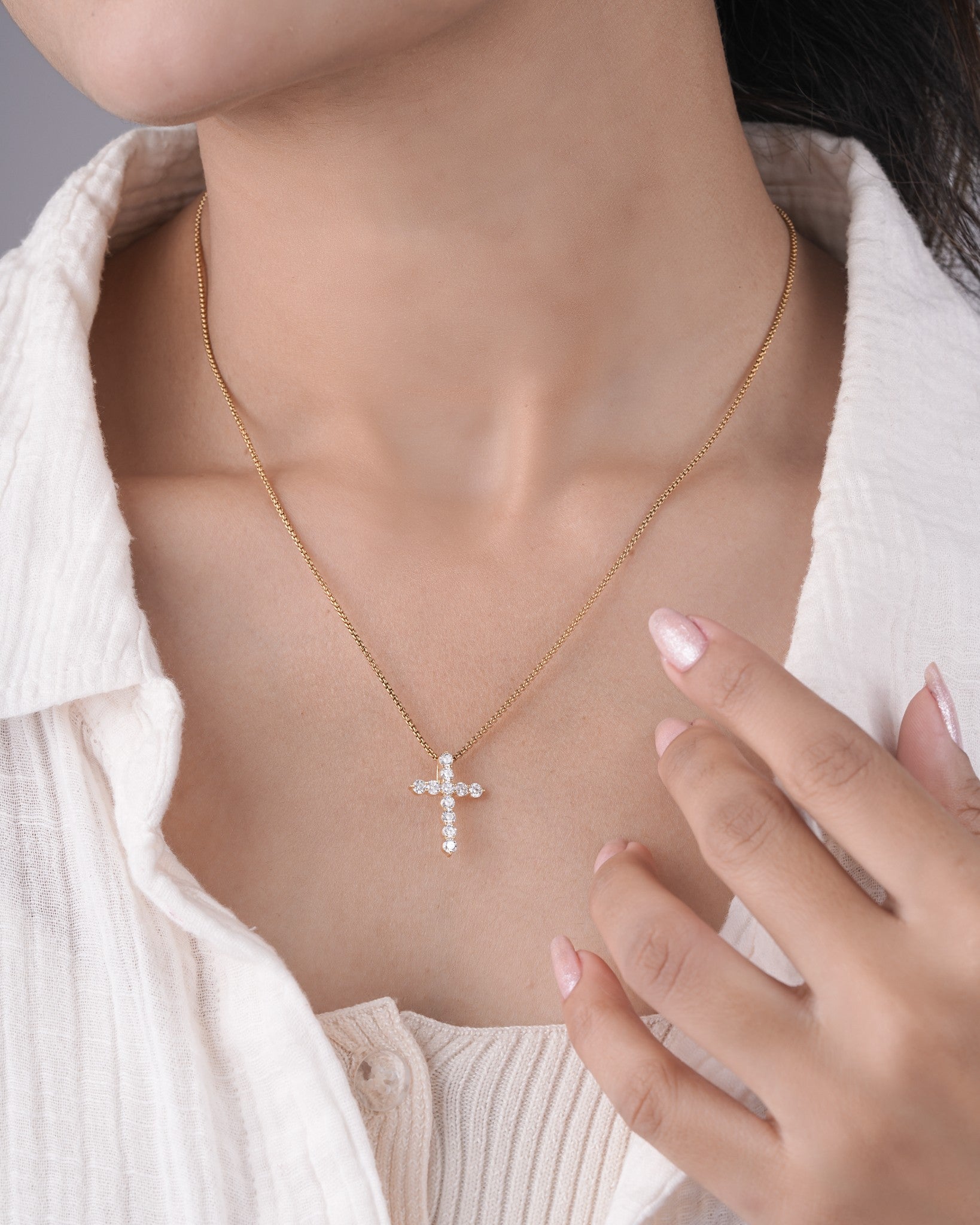 Person wearing cross diamond pendant.