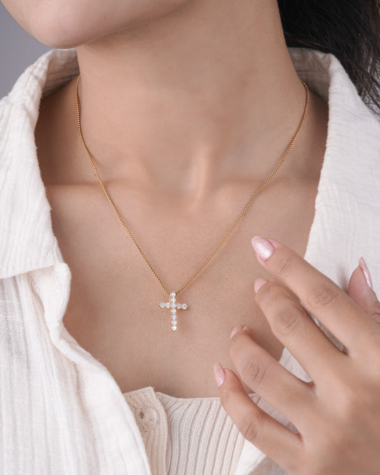 Person wearing cross diamond pendant.