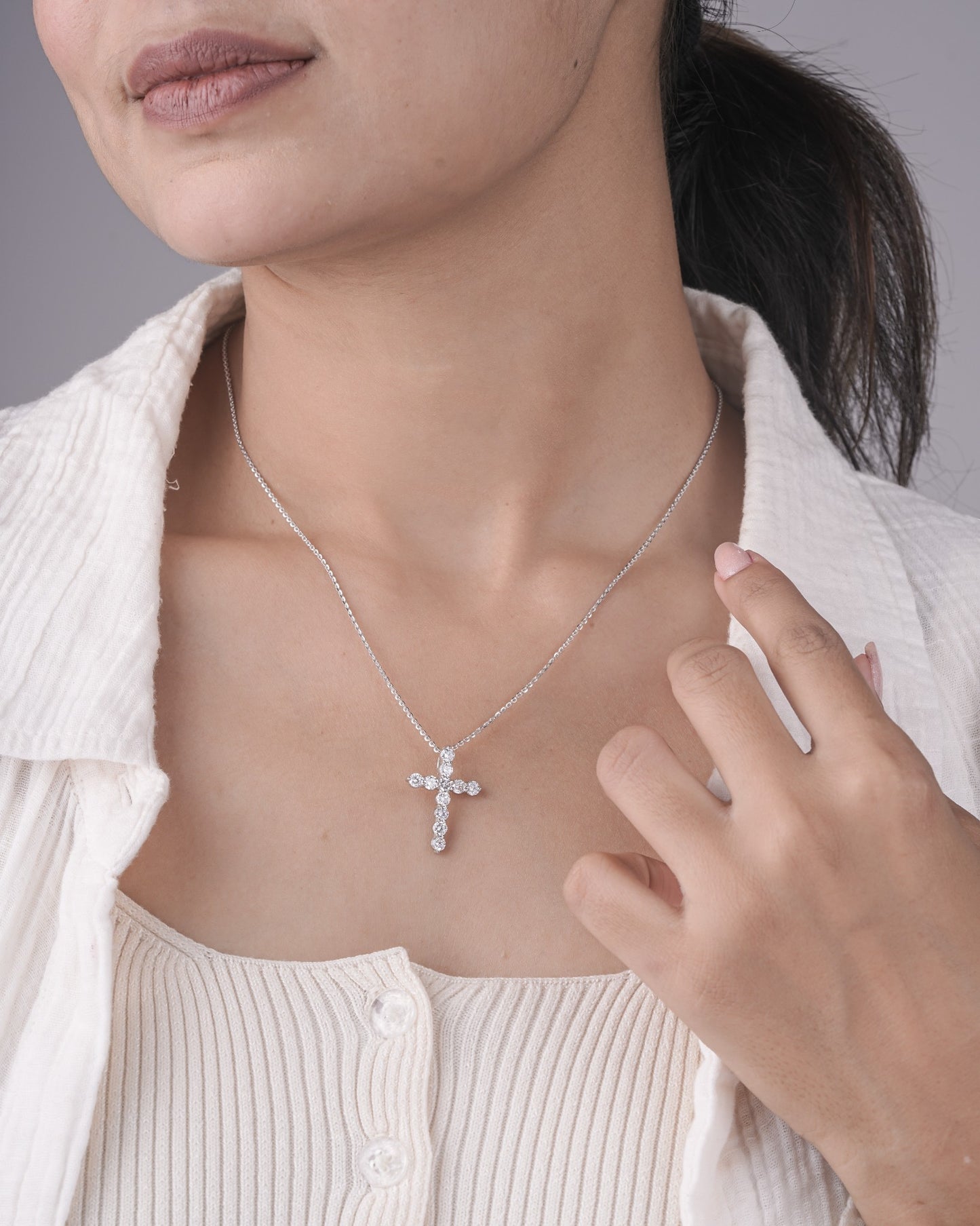 Person wearing cross diamond pendant in white gold.
