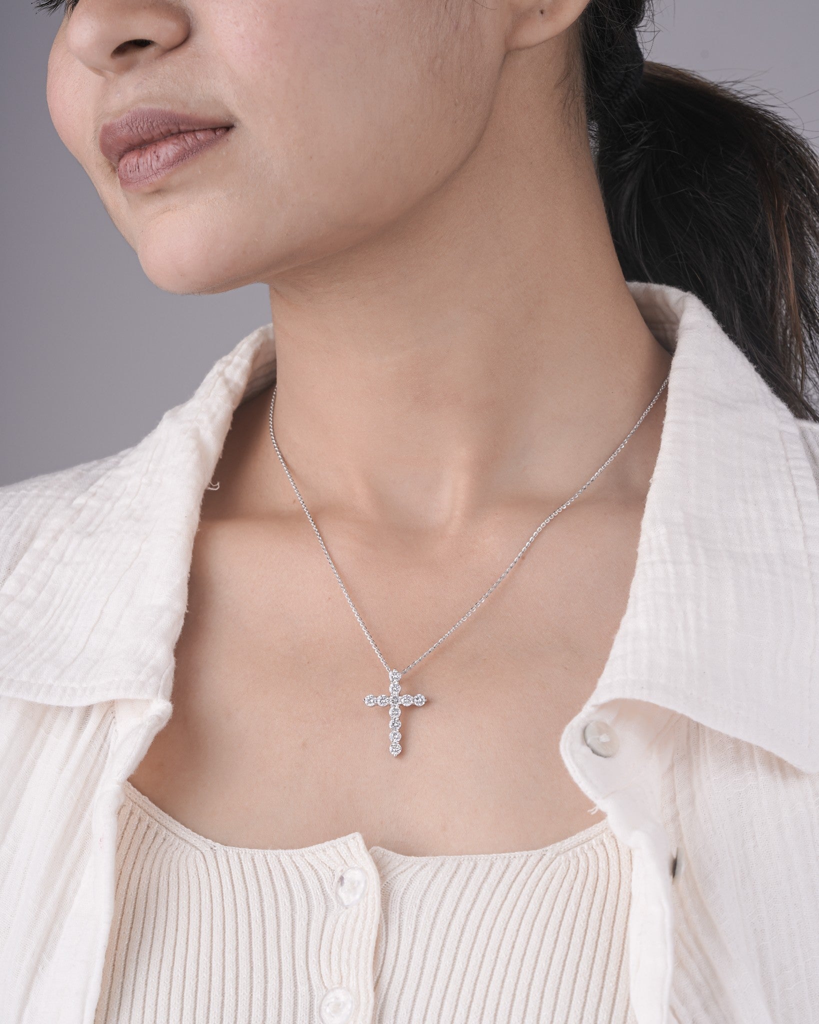 Person wearing cross diamond pendant in white gold.
