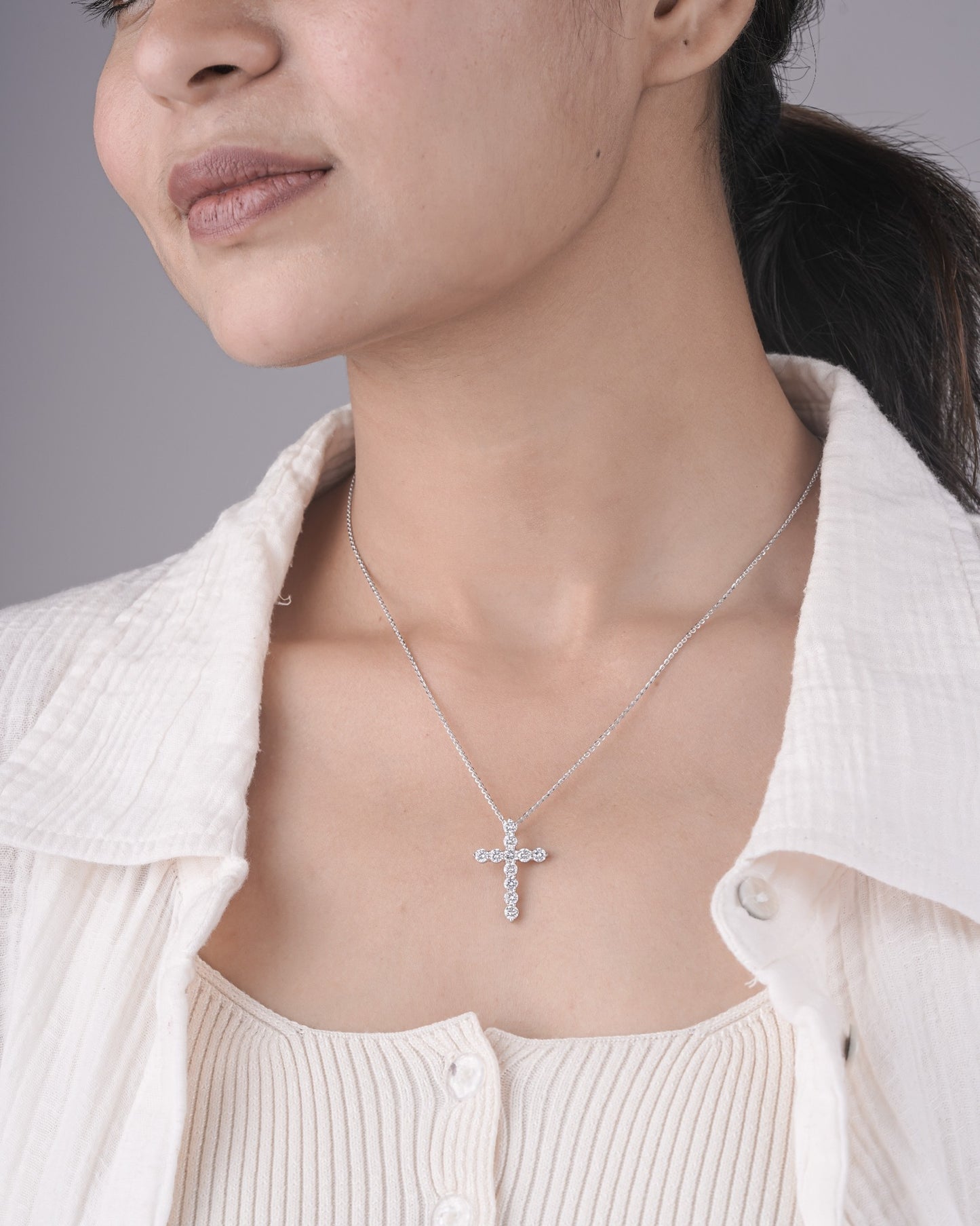Person wearing cross diamond pendant in white gold.
