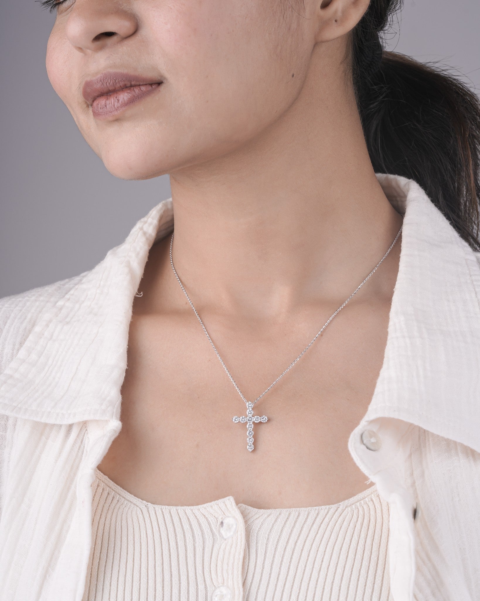 Person wearing cross diamond pendant in white gold.
