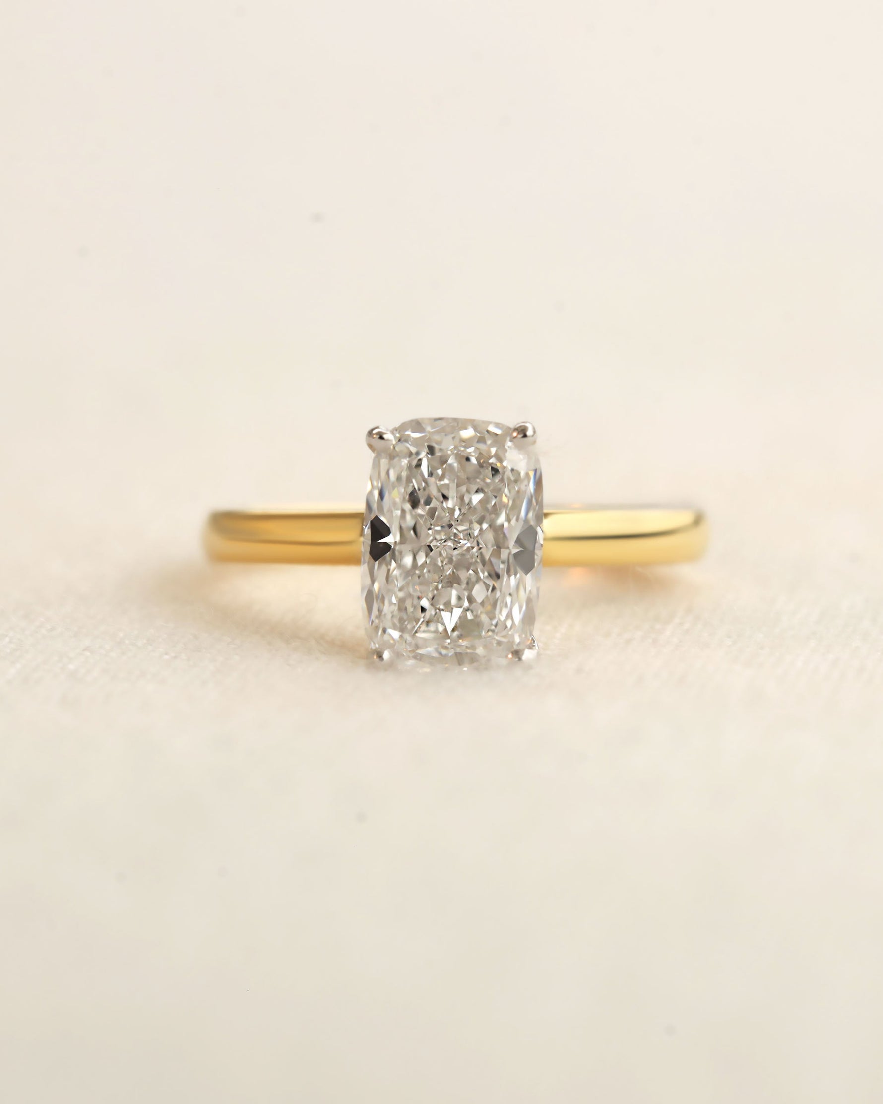 Gold ring with a large diamond on a beige background.