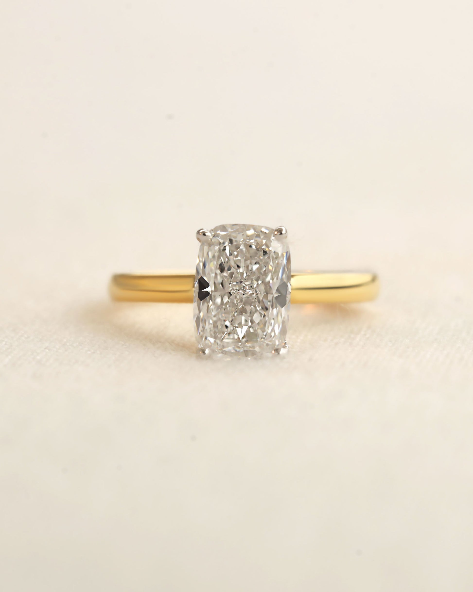 Gold ring with a large diamond on a beige background.