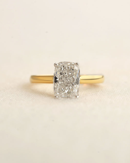 Gold ring with a large diamond on a beige background.