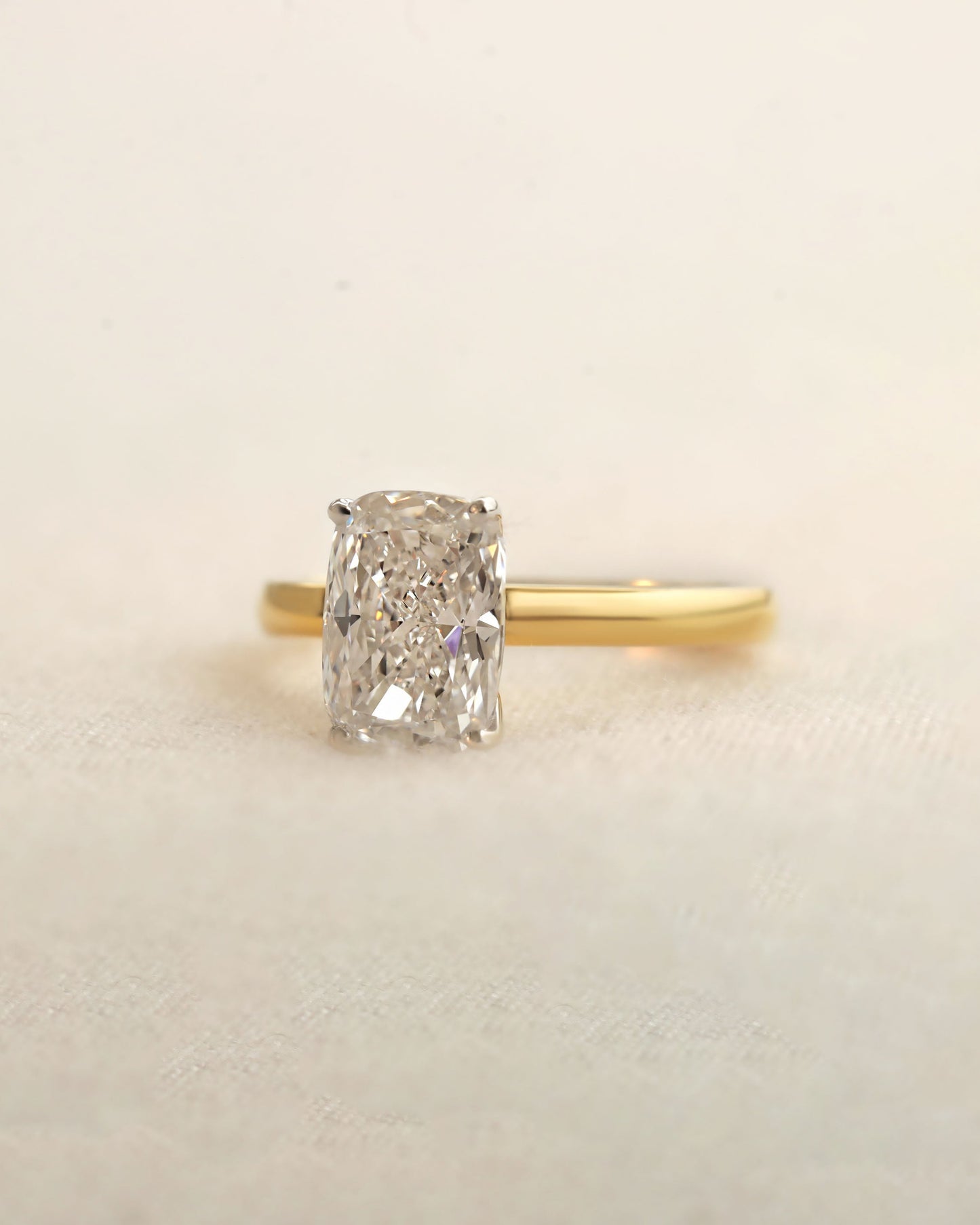 Gold ring with a diamond on a beige background.