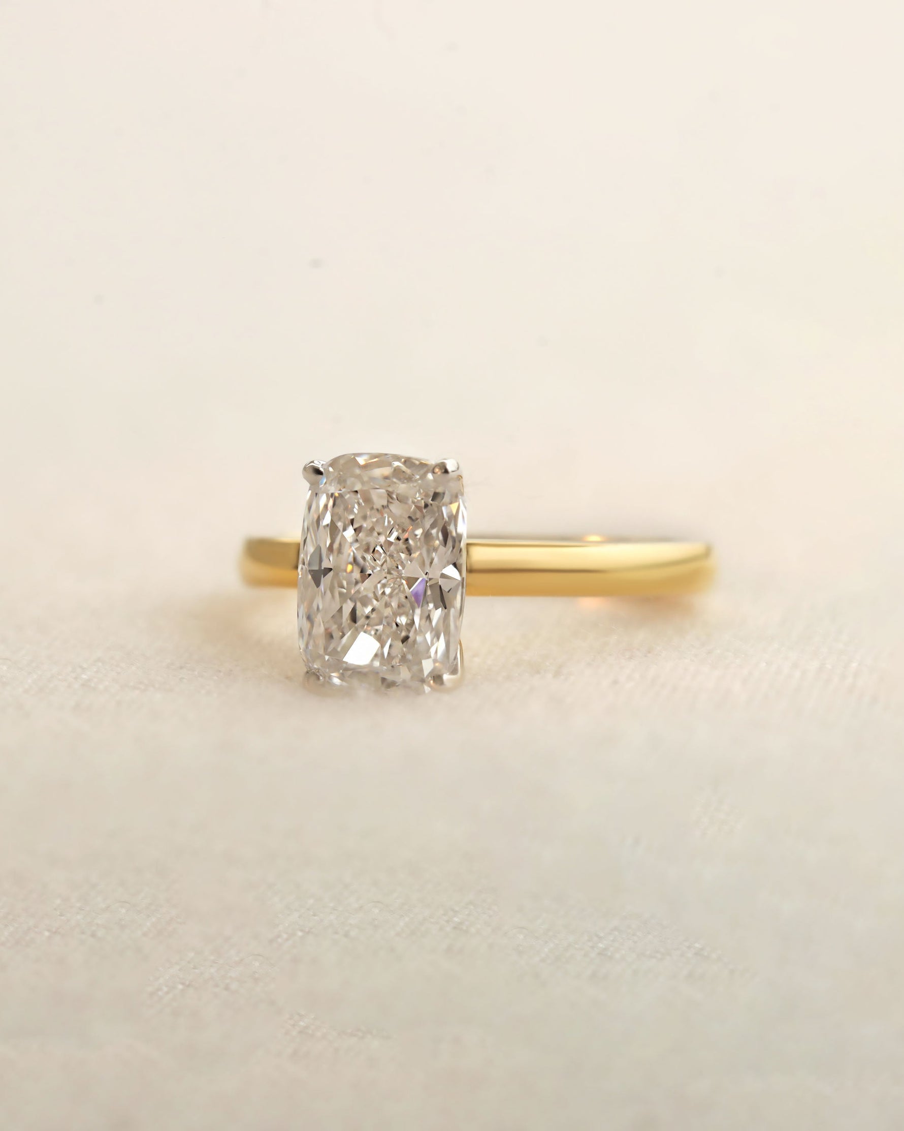 Gold ring with a diamond on a beige background.