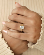 Hand wearing a diamond ring on a beige background.