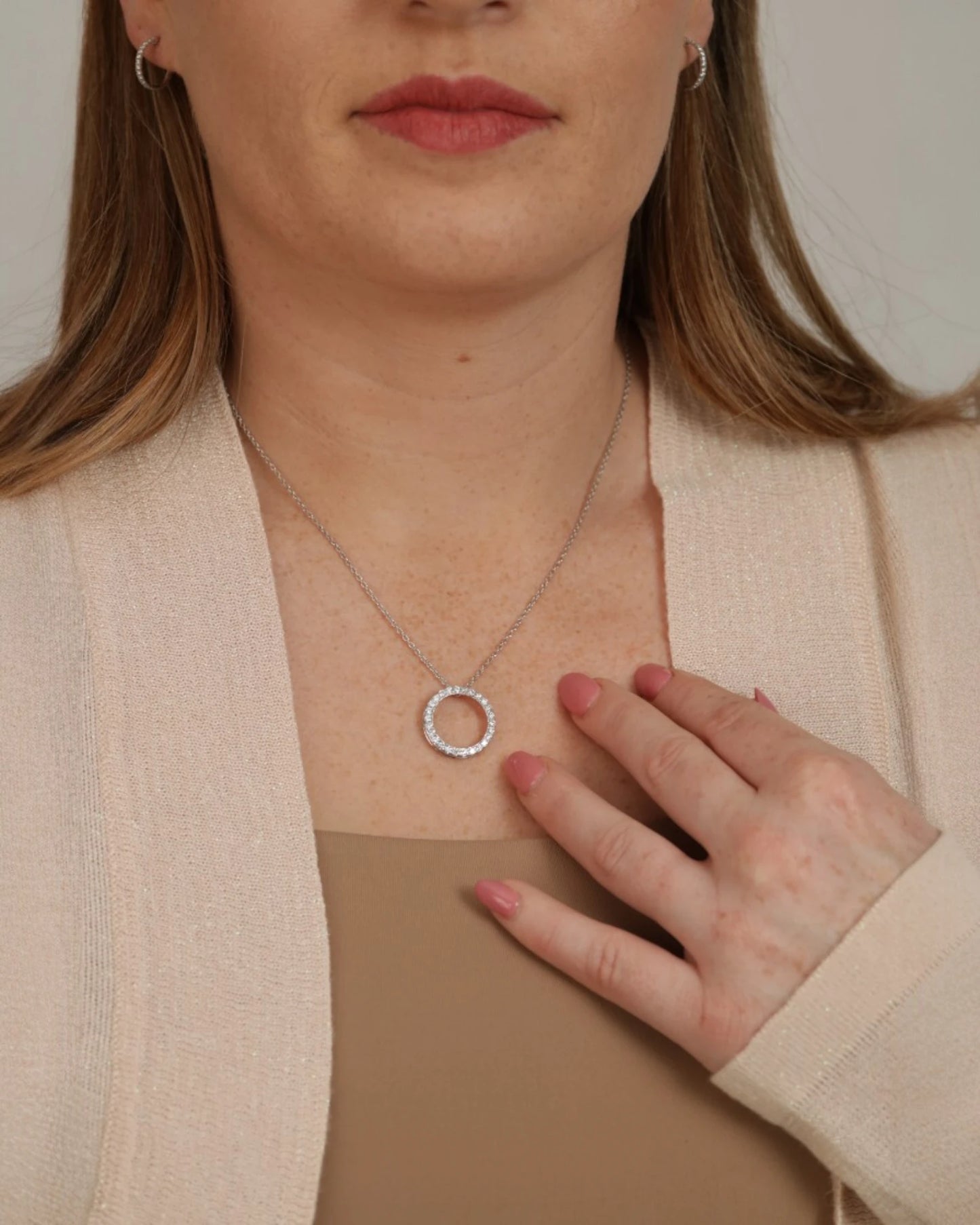 Person wearing diamond circle pendant necklace.