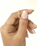 Hand holding a gold diamond band.