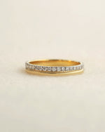 A yellow gold diamond band on a white background.