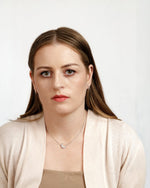 Person wearing diamond huggie hoop earrings.