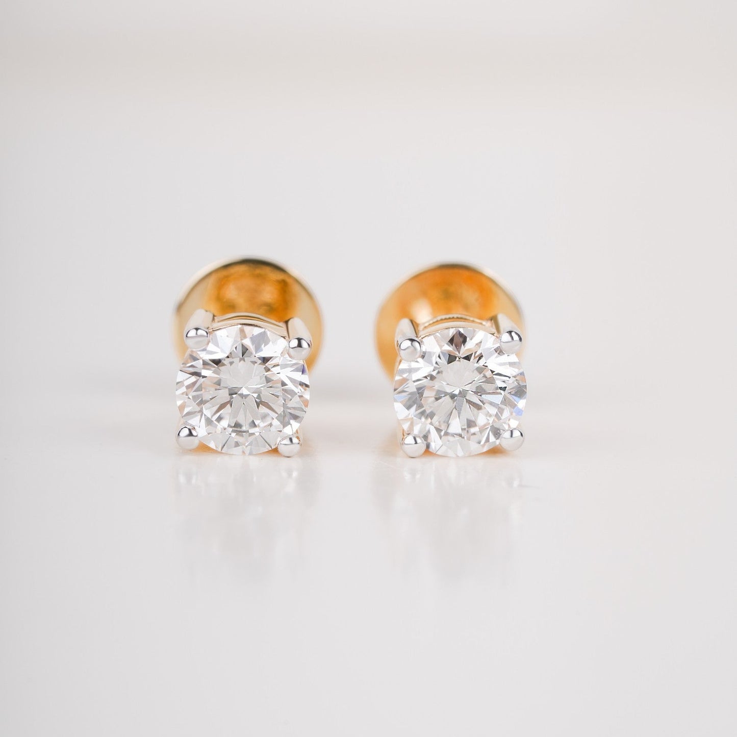 Close up shot of diamond studs earrings in yellow gold.