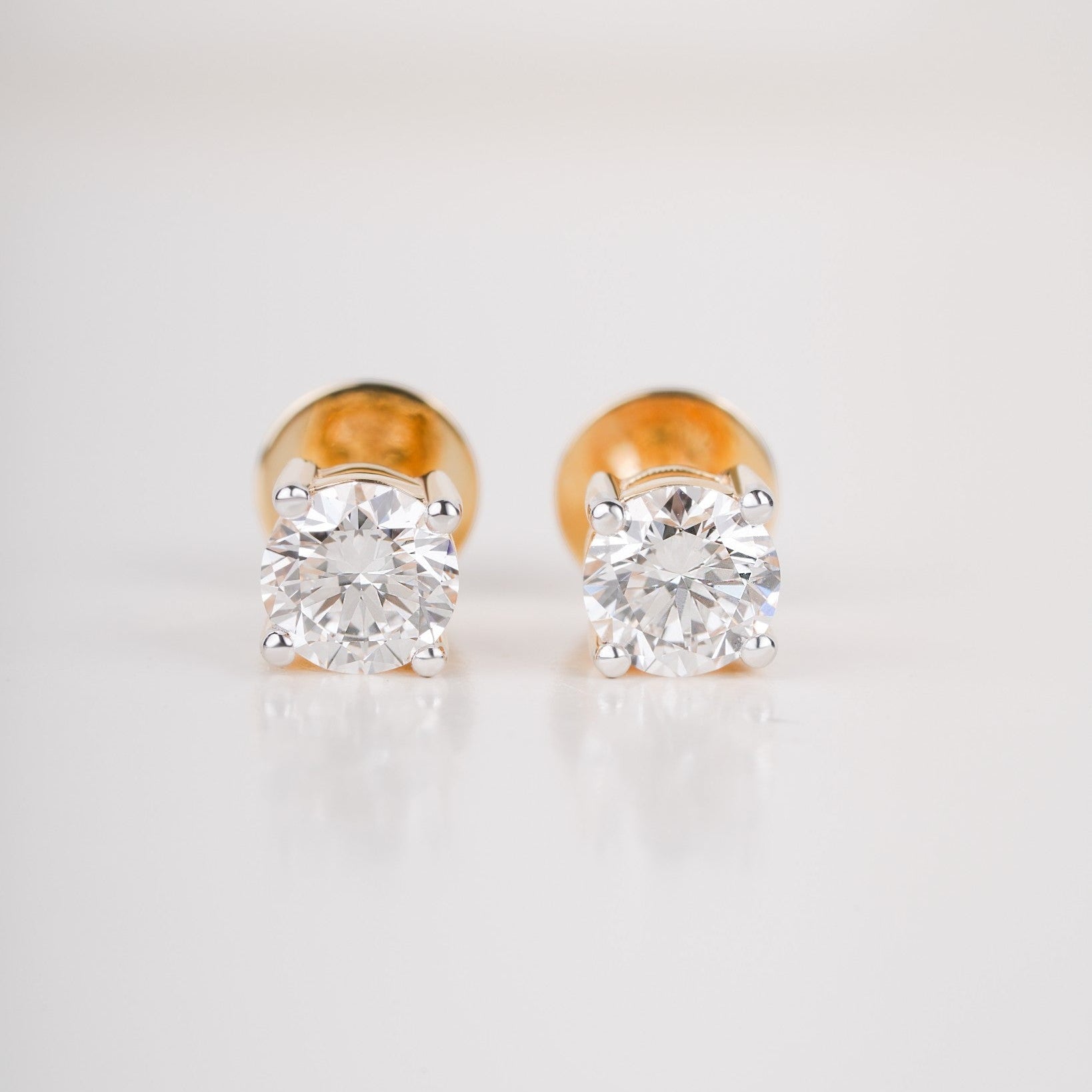 Close up shot of diamond studs earrings in yellow gold.