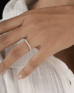  Hand wearing full eternity diamond ring band in yellow gold.