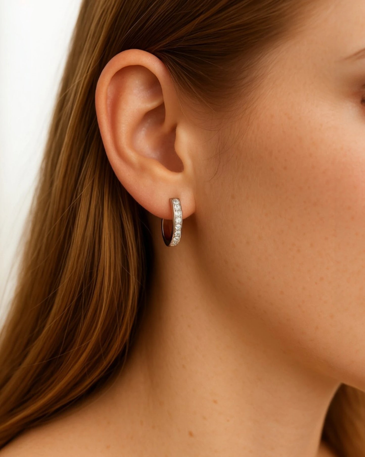 Person wearing huggie earrings with 0.17 Carat TW of diamonds.