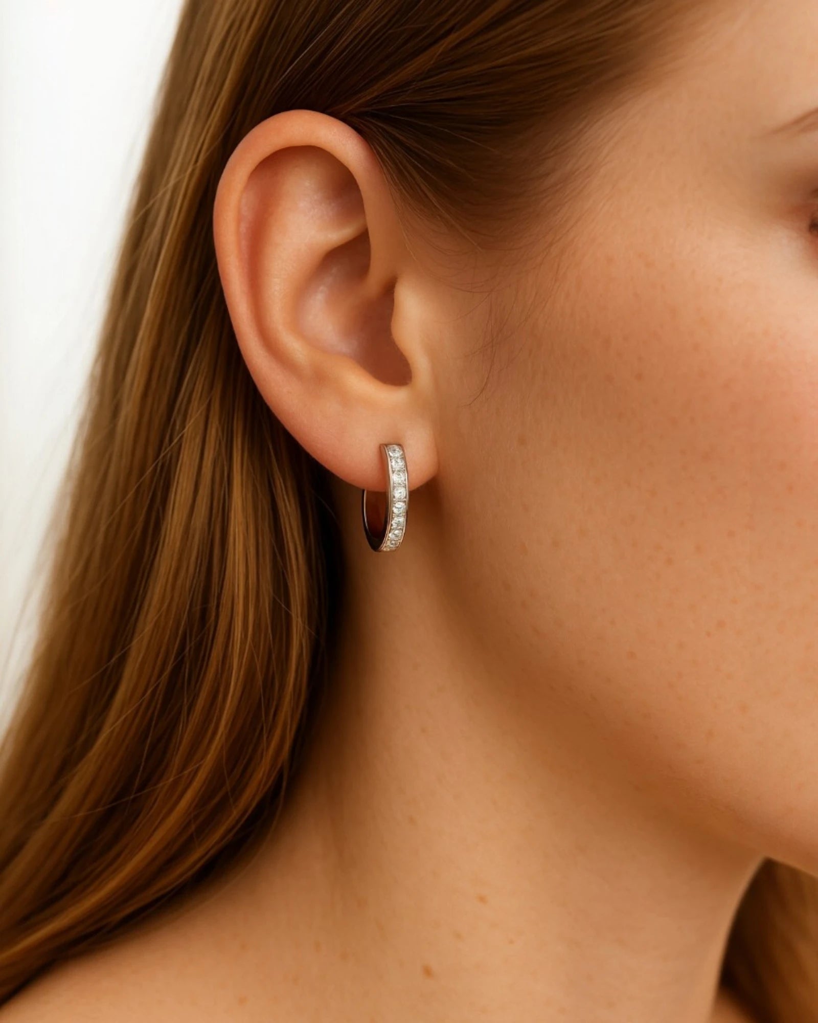 Person wearing huggie earrings with 0.17 Carat TW of diamonds.