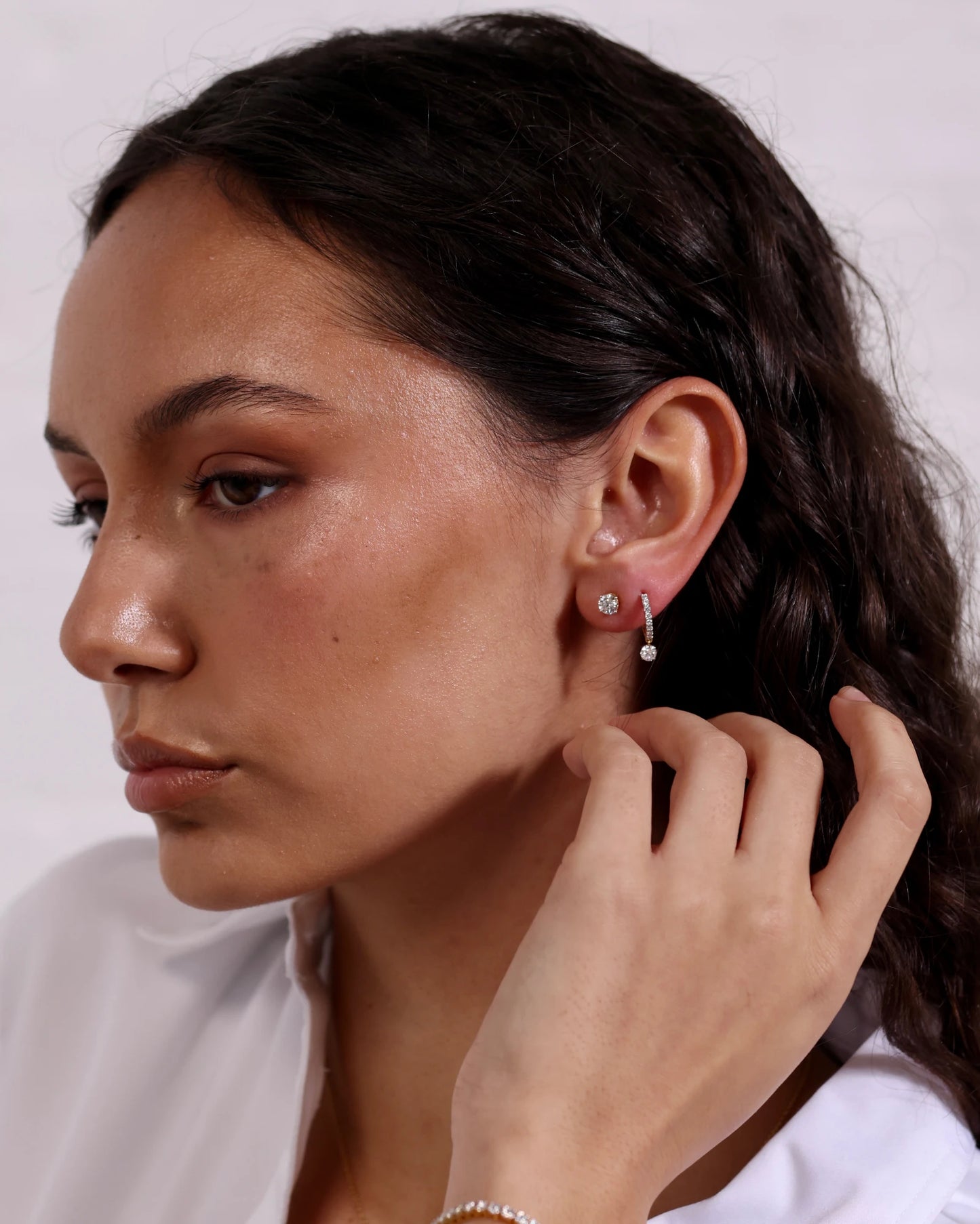 Person wearing diamond drop hoop earrings.