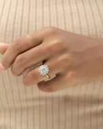 Hand wearing a diamond ring on a beige background.